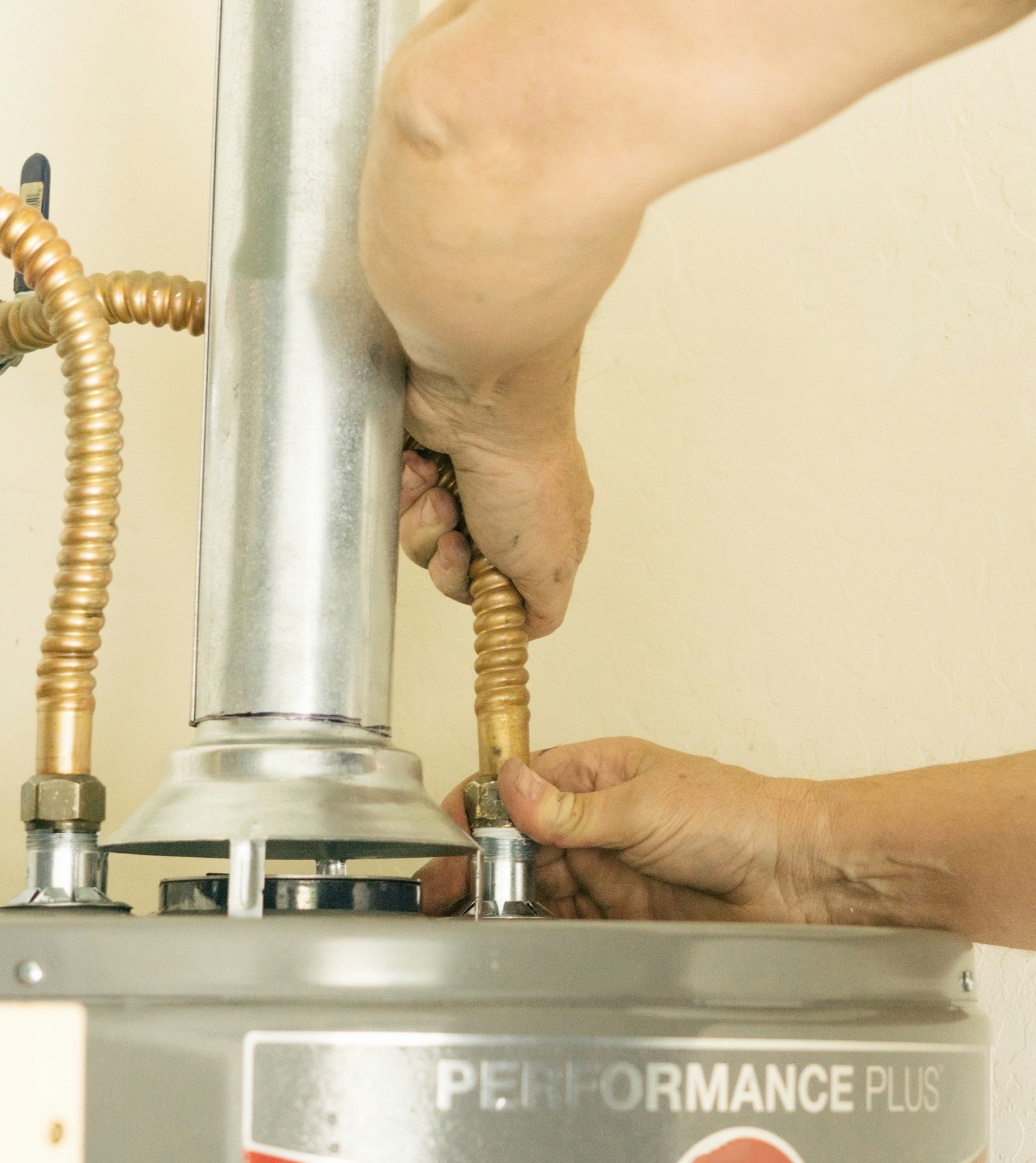 Adult male hands on water line going into a hot water heater